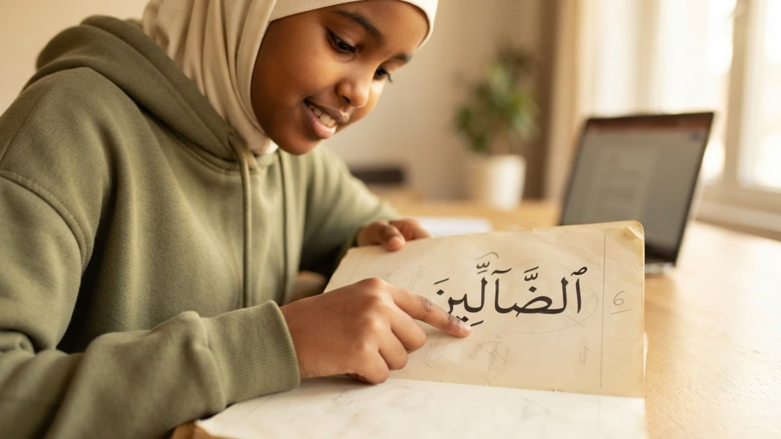 Hand tracing Arabic madd letters while practicing Tajweed madd rules from Surah al-Fatiha